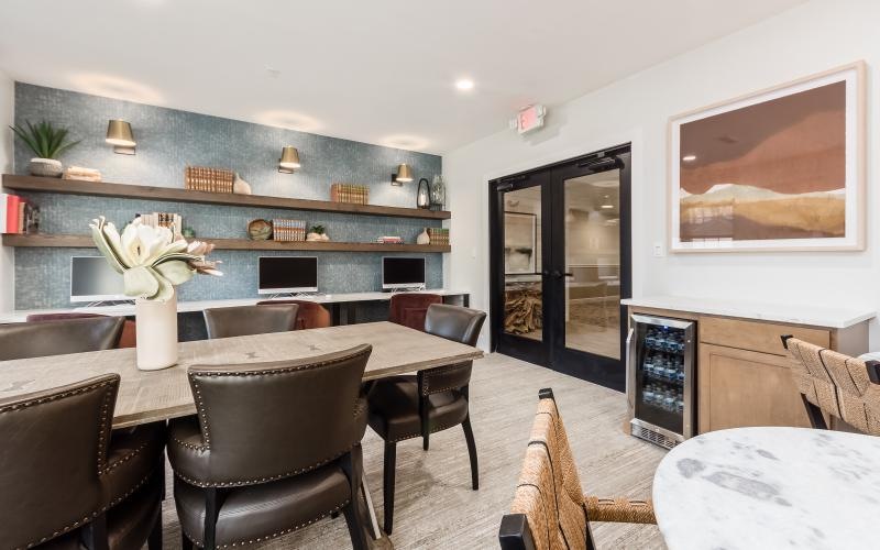 a room with a table chairs and a shelf with pictures on it
